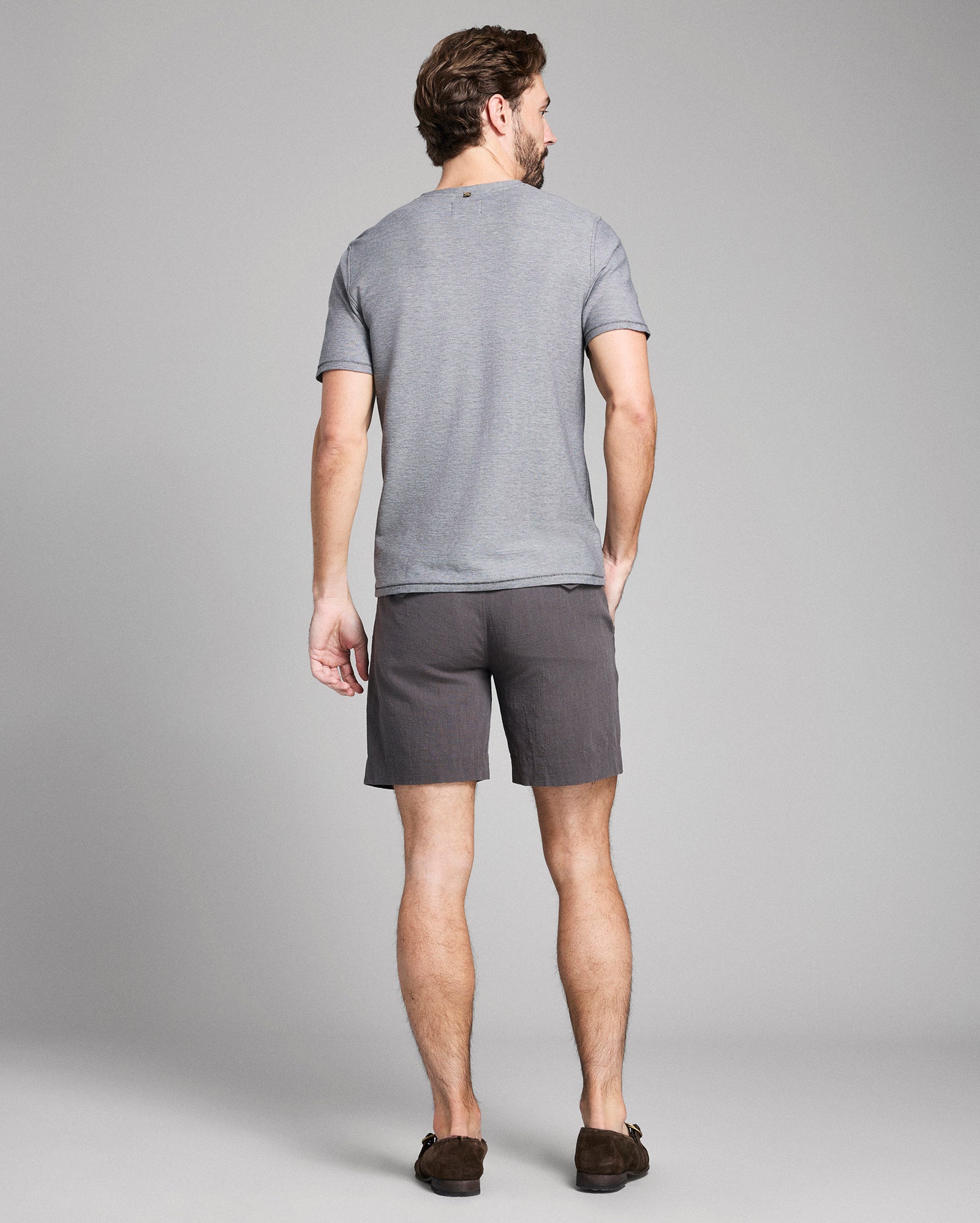 Man wearing a gray t-shirt and shorts on a plain background