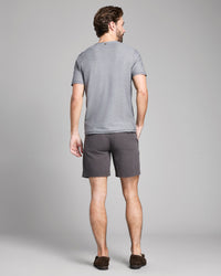 Man wearing a gray t-shirt and shorts on a plain background
