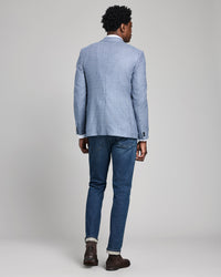 Person wearing a blue checkered blazer and jeans on a plain background