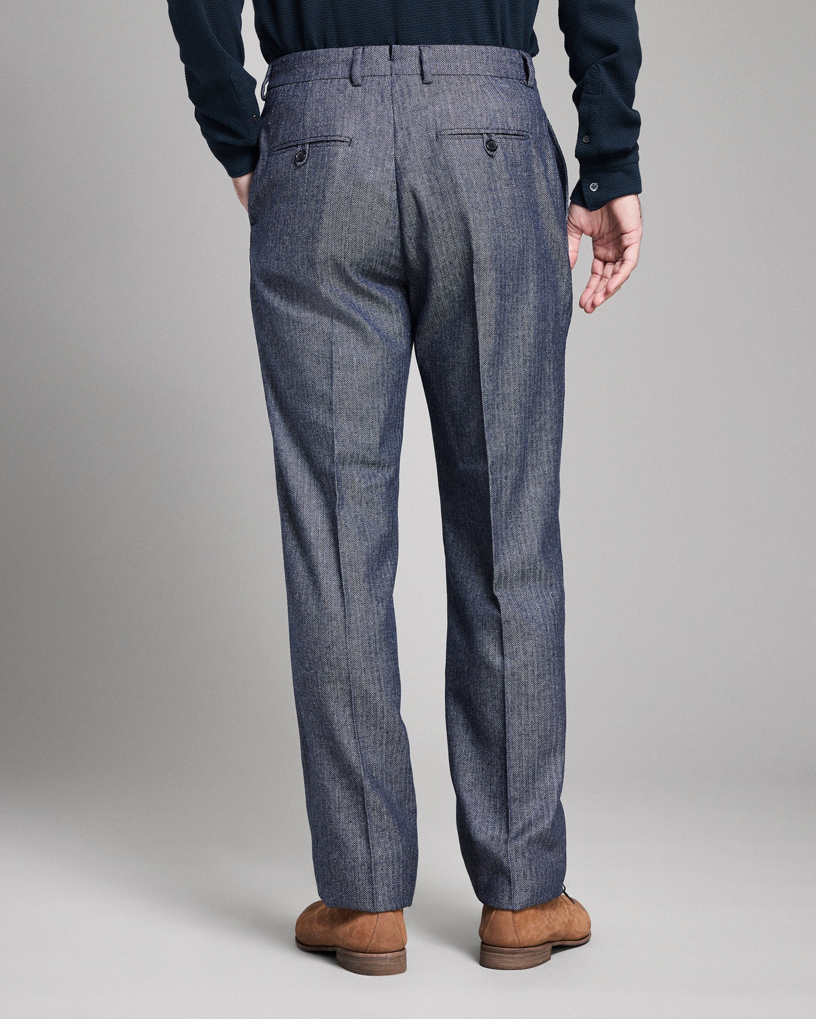 Back of blue dress pants worn by a person on a plain background