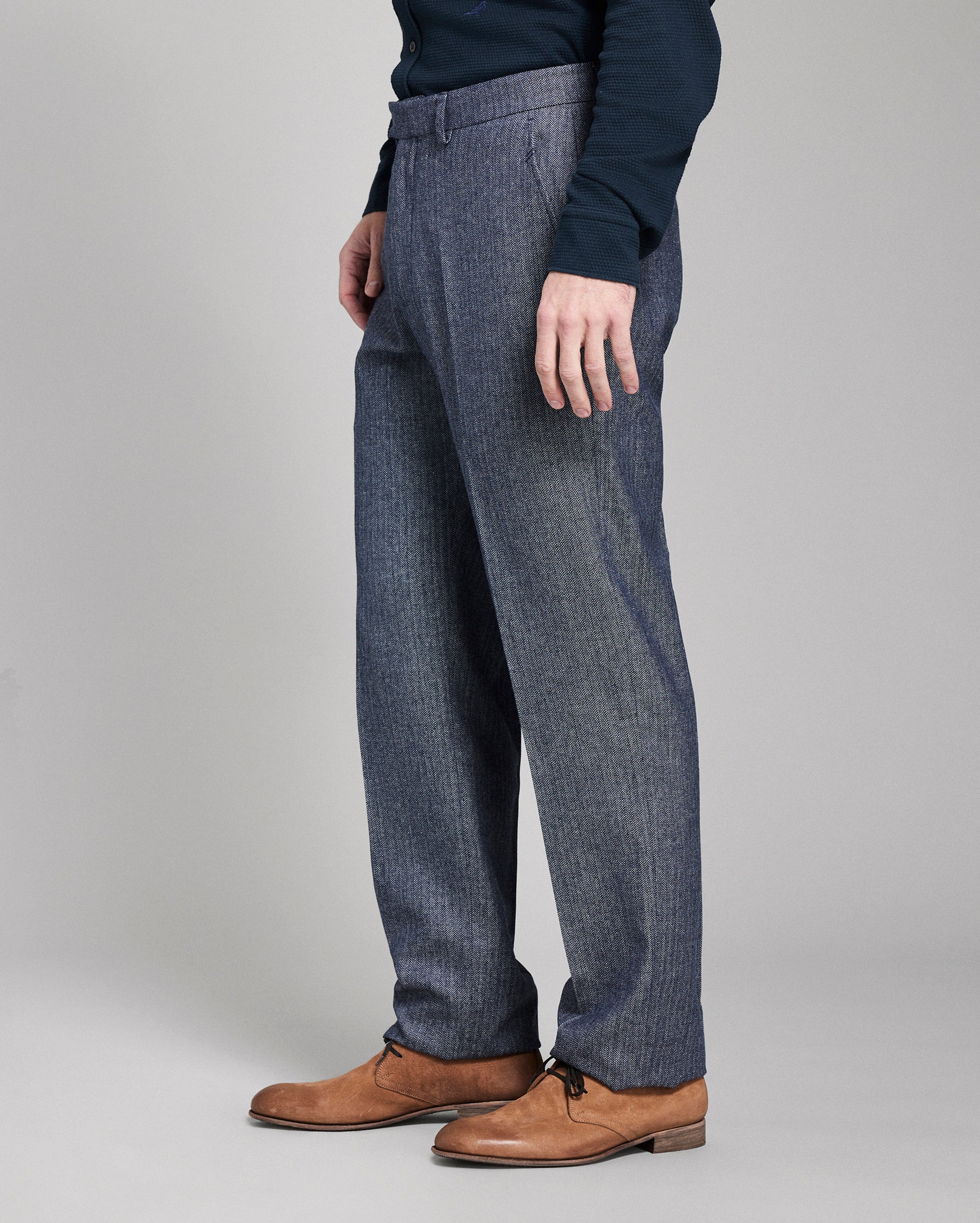 Person wearing blue checkered pants and brown shoes on a gray background