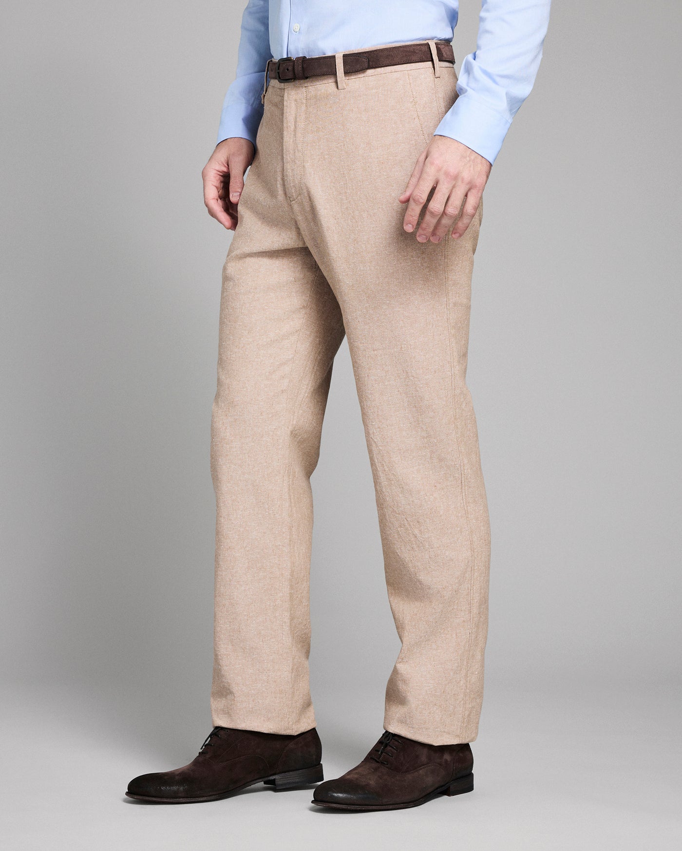 Man wearing beige dress pants with a plain background