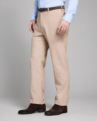 Man wearing beige dress pants with a plain background