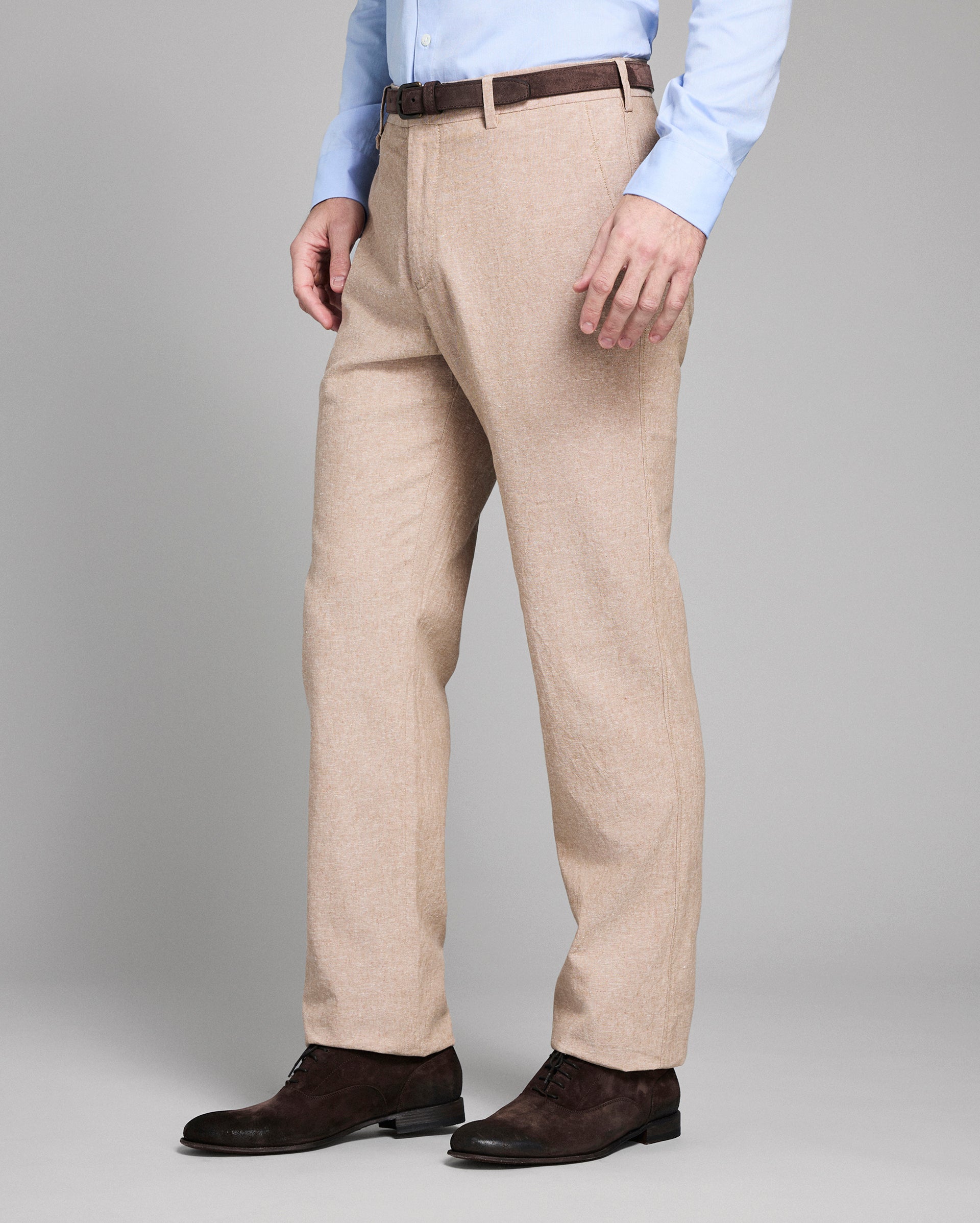 Man wearing beige dress pants with a plain background