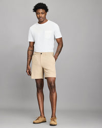 Man wearing a white t-shirt and beige shorts on a gray background