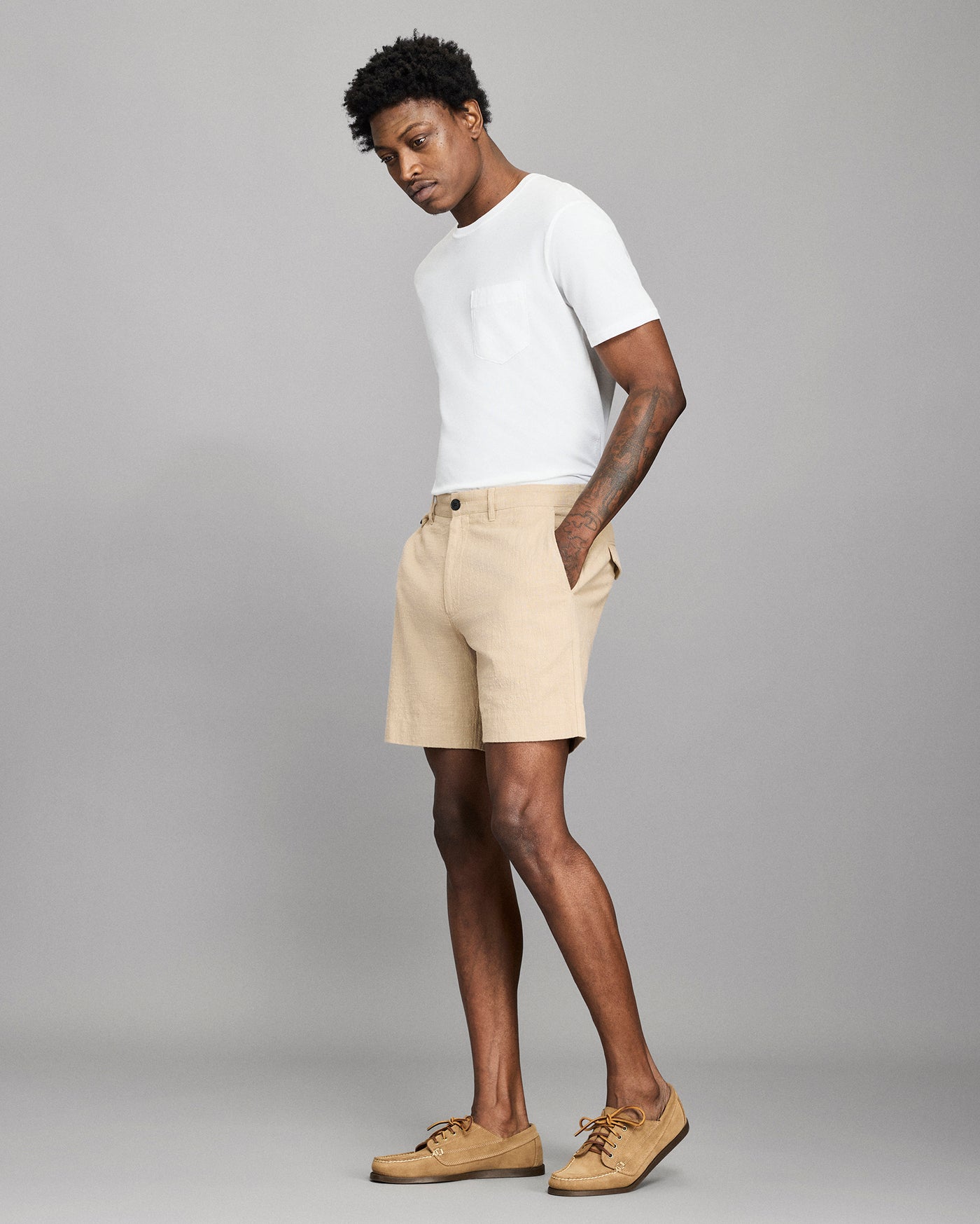 Man wearing a white t-shirt and beige shorts on a gray background