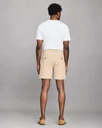 Man wearing beige shorts and a white t-shirt on a gray background