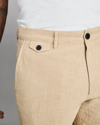 Beige pants with black buttons on a neutral background
