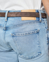 Light blue jeans with a brown belt and visible brand label.