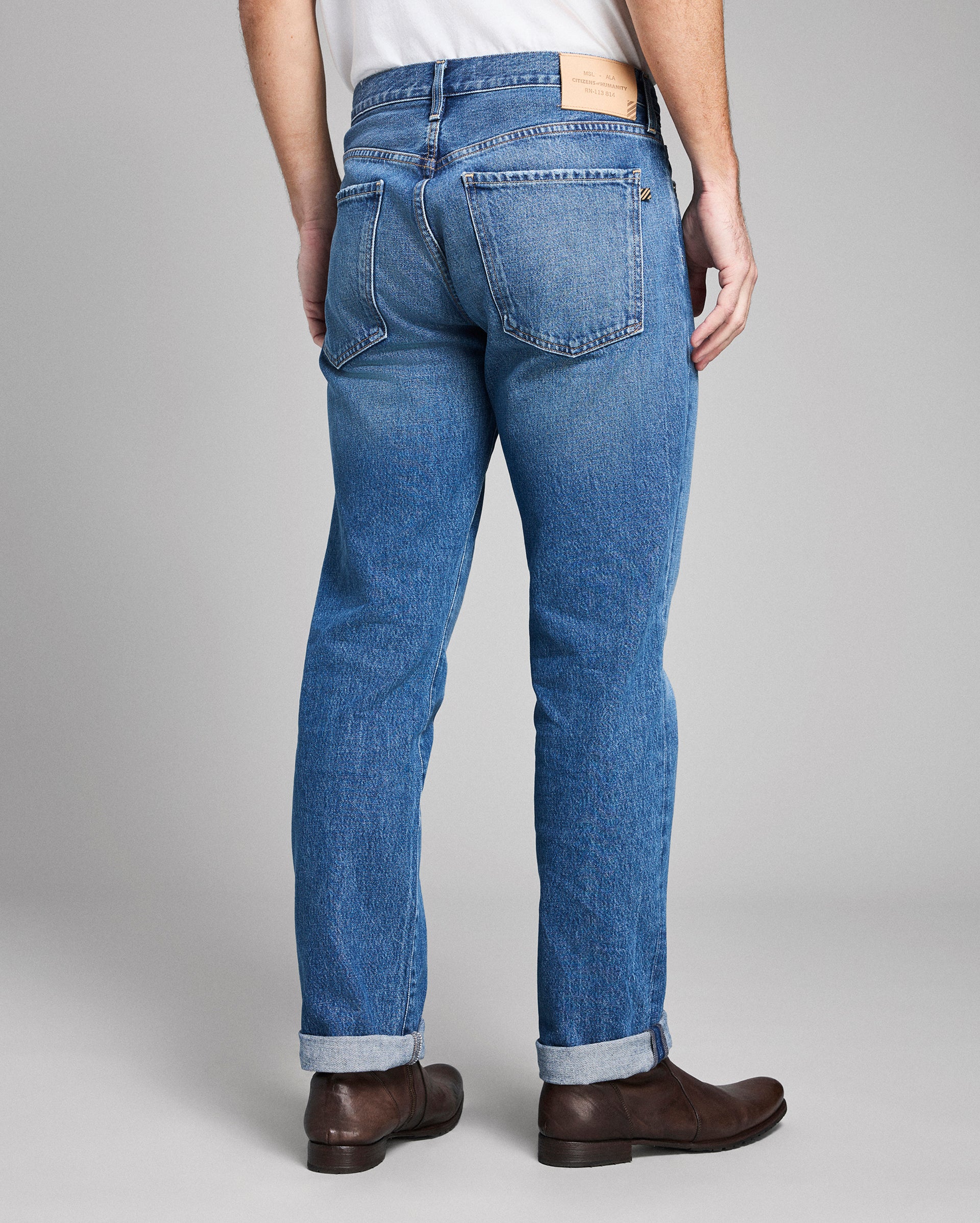 Person wearing blue jeans with a plain background