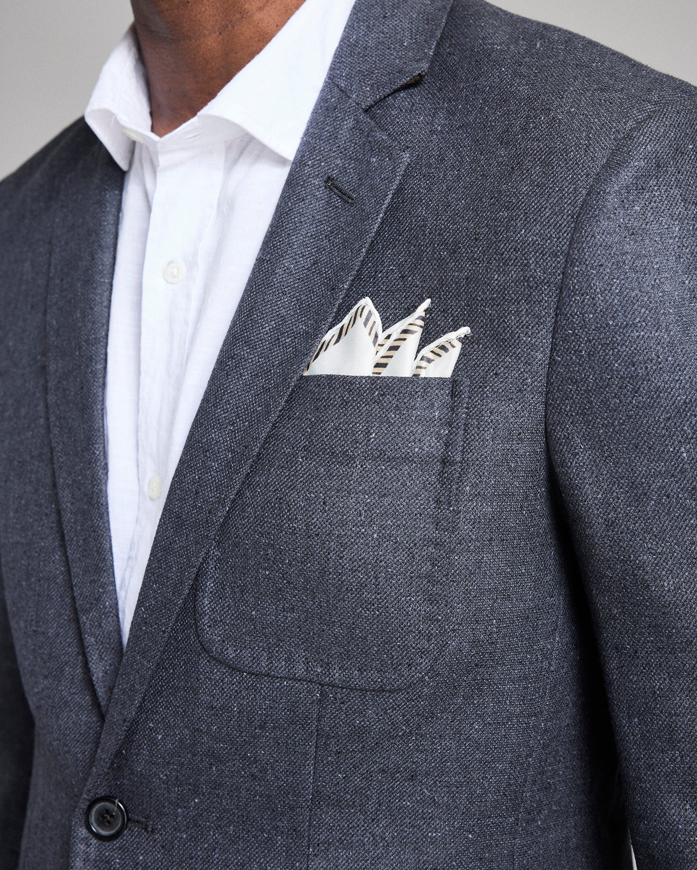 Gray suit jacket with a white shirt and patterned pocket square.