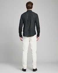 Man wearing a black shirt and white pants on a gray background
