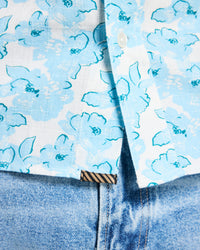 Close-up of a blue floral shirt with a patterned tie and jeans.