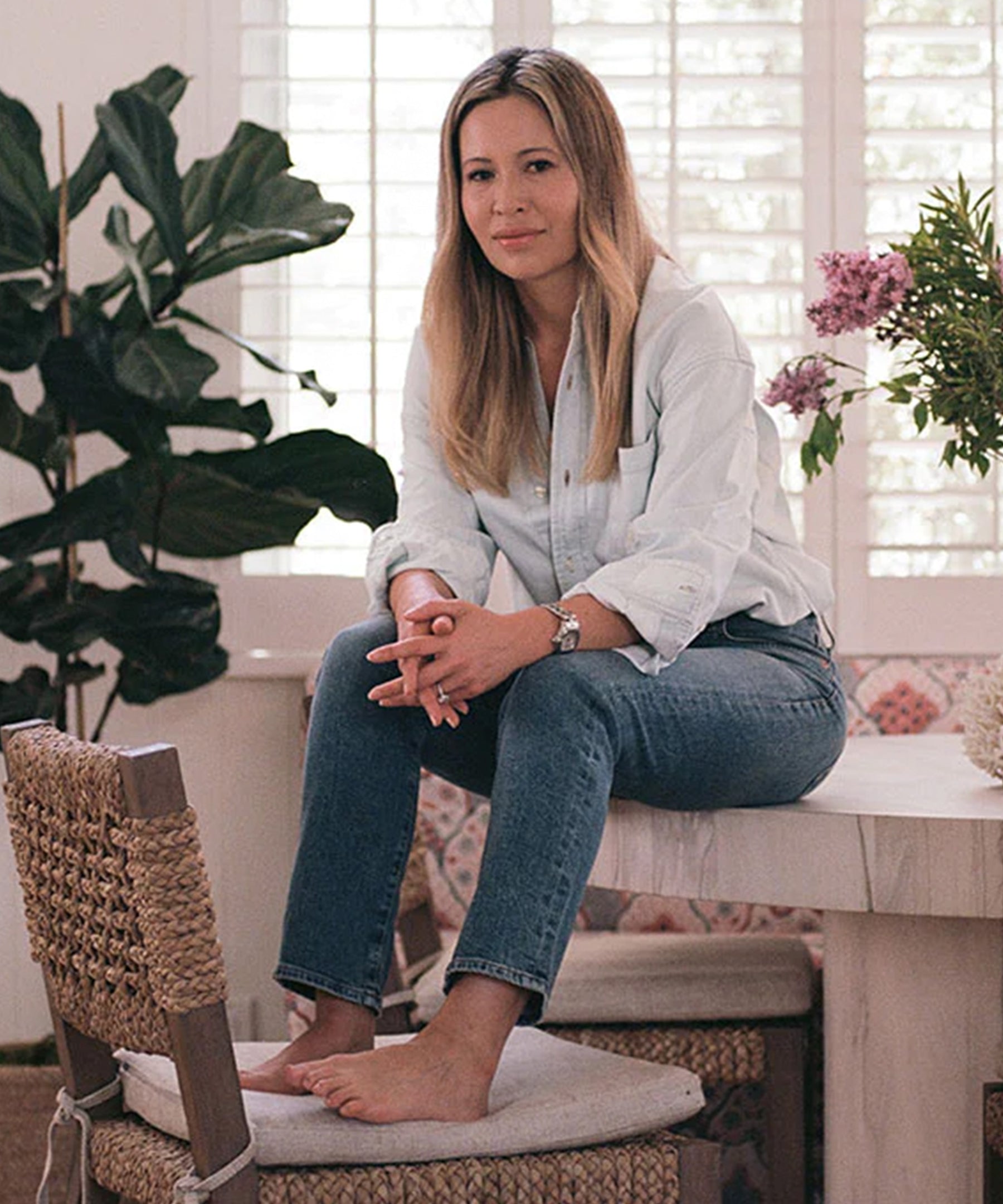 Marianne McDonald, Creative Director at Citizens of Humanity, sits on a table in a white room.