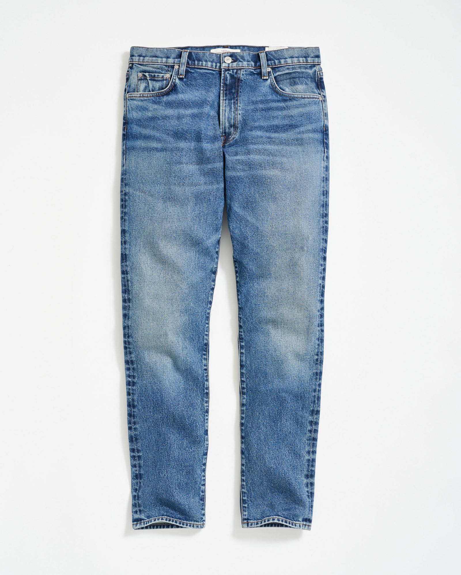 A pair of classic blue denim jeans with a slight faded effect, front pockets, belt loops, and a button fly, laid flat on a white background.