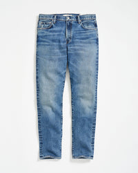 A pair of classic blue denim jeans with a slight faded effect, front pockets, belt loops, and a button fly, laid flat on a white background.