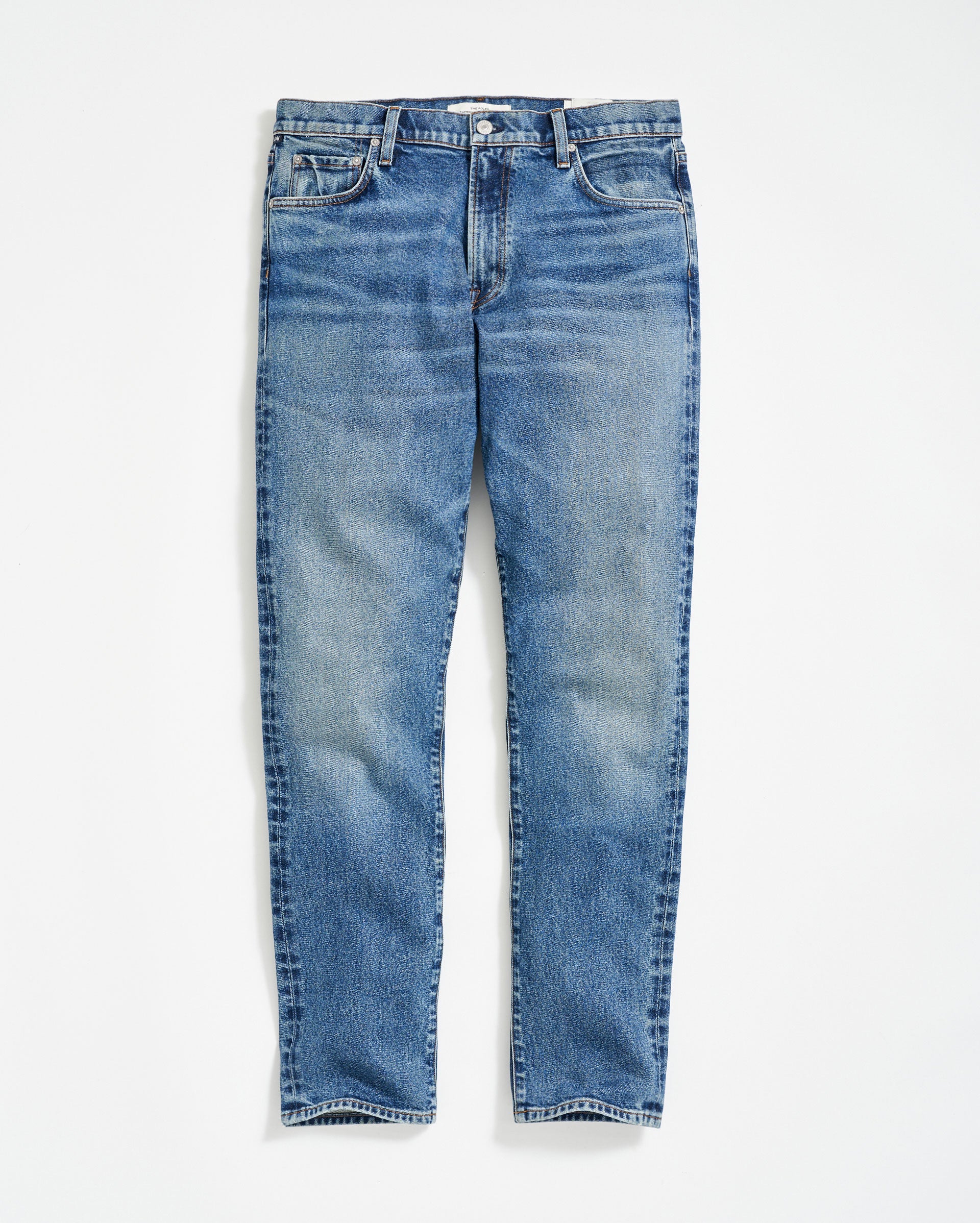 A pair of classic blue denim jeans with a slight faded effect, front pockets, belt loops, and a button fly, laid flat on a white background.