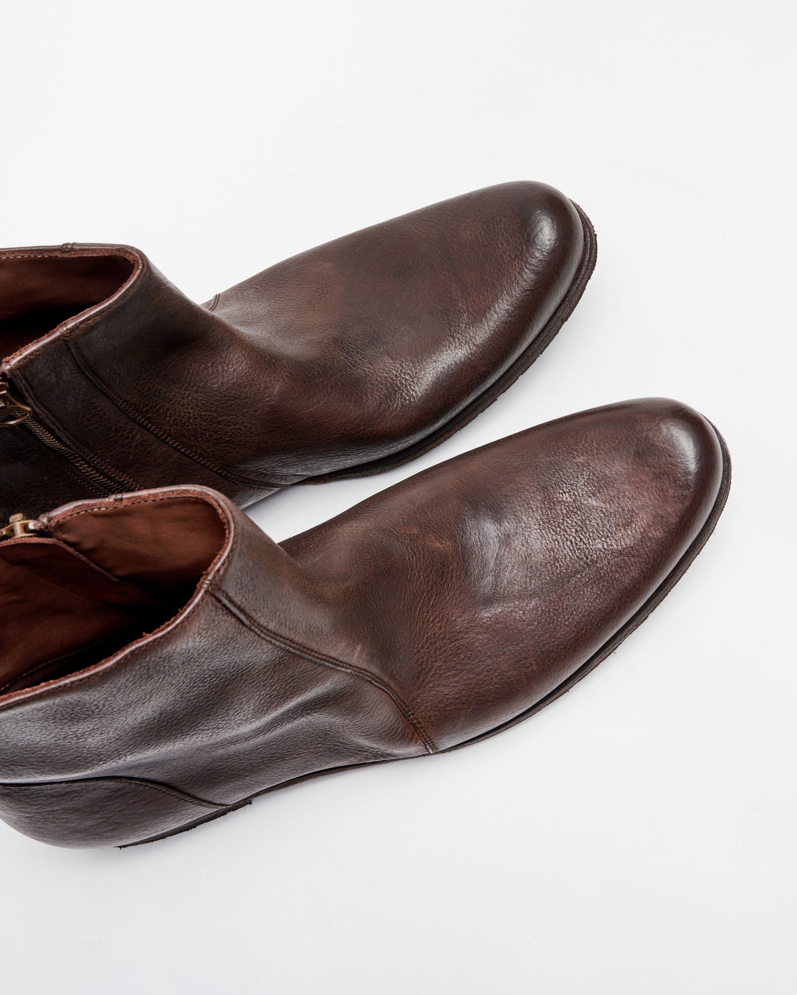 A pair of brown leather ankle boots with side zippers, shown from above on a white background.