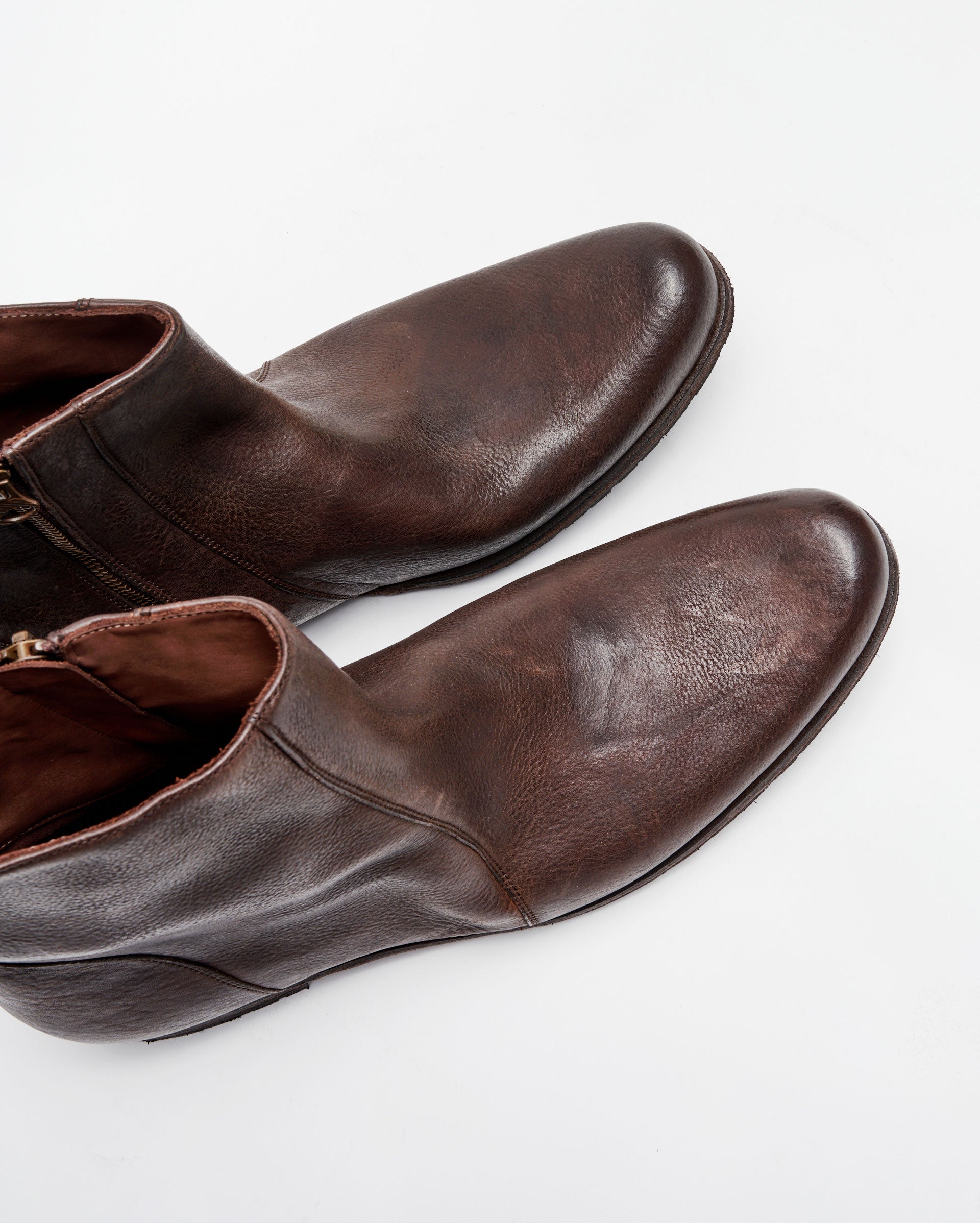 A pair of brown leather ankle boots with side zippers, shown from above on a white background.