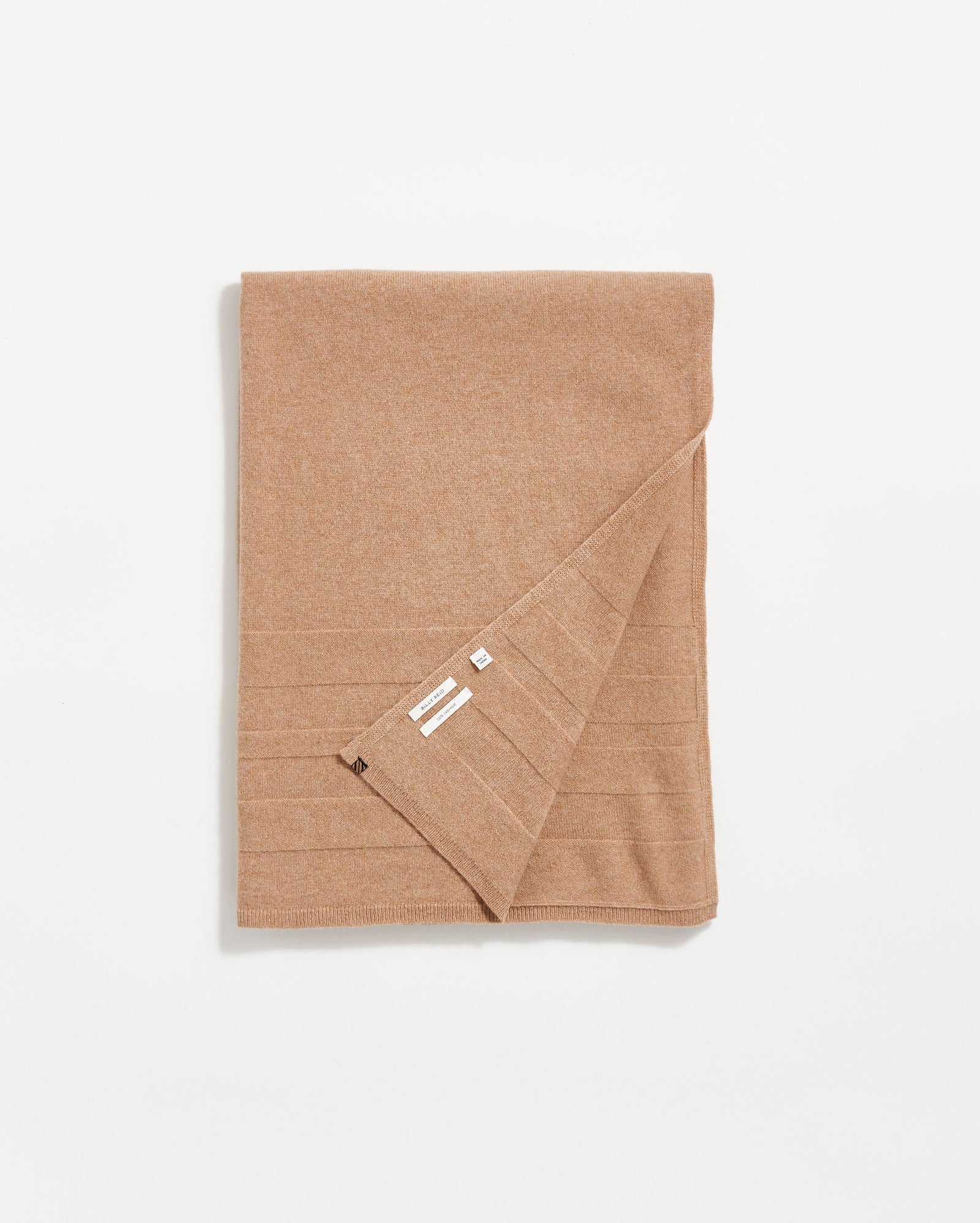 A neatly folded camel-colored blanket with visible tags on one corner, displayed on a white background.
