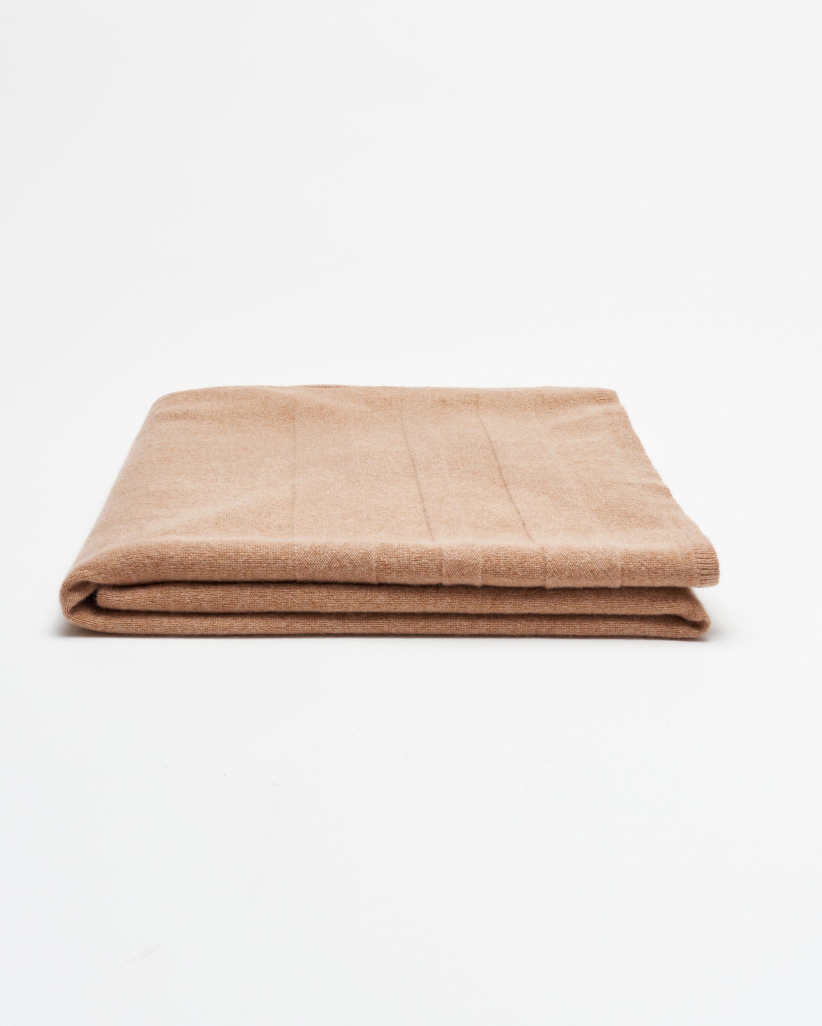 A neatly folded light brown blanket is placed on a plain white background.