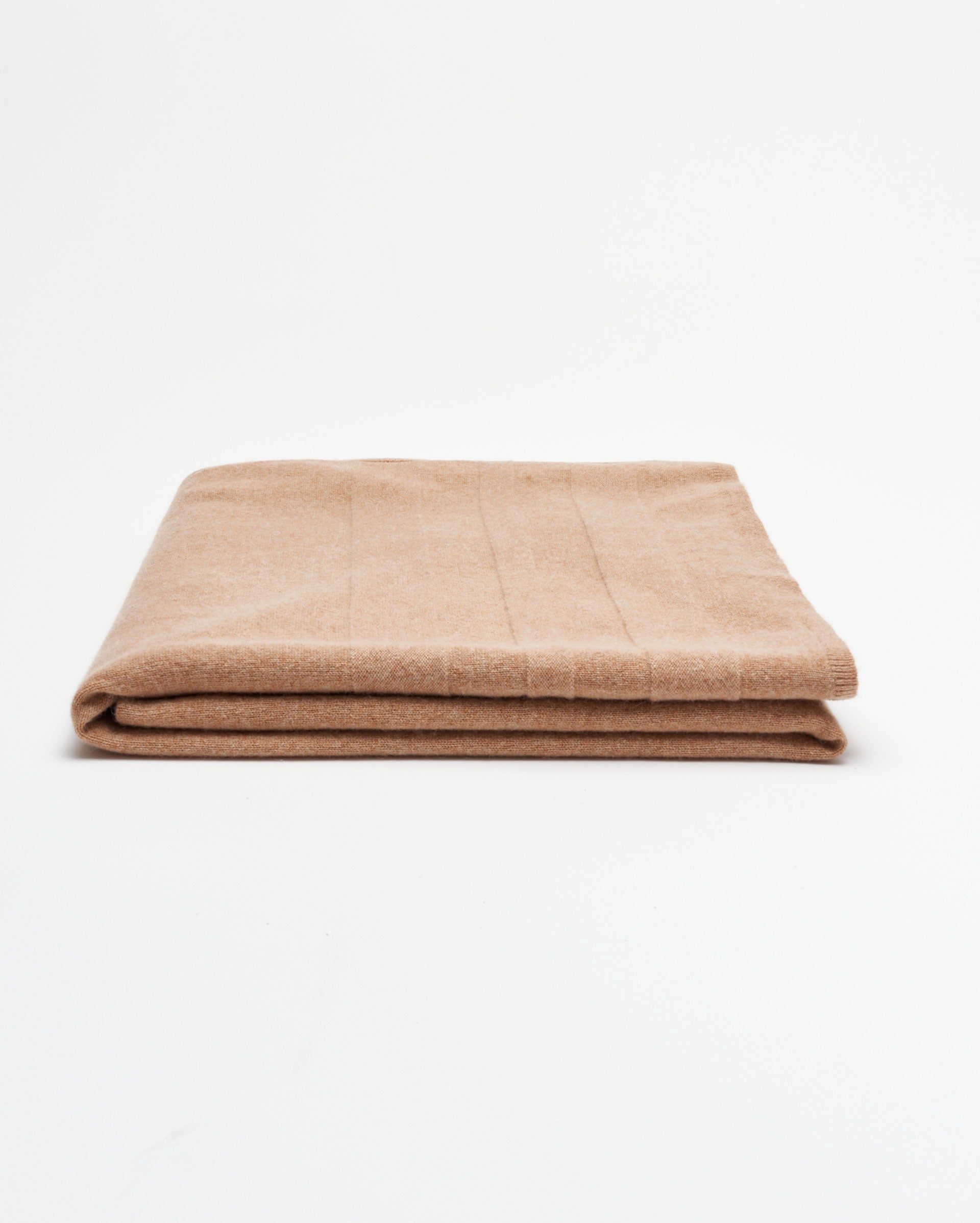 A neatly folded light brown blanket is placed on a plain white background.