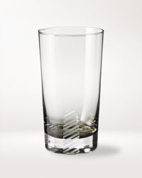 A clear empty glass tumbler with a vertical, diagonal-striped frosted pattern near the base, placed on a plain white background.