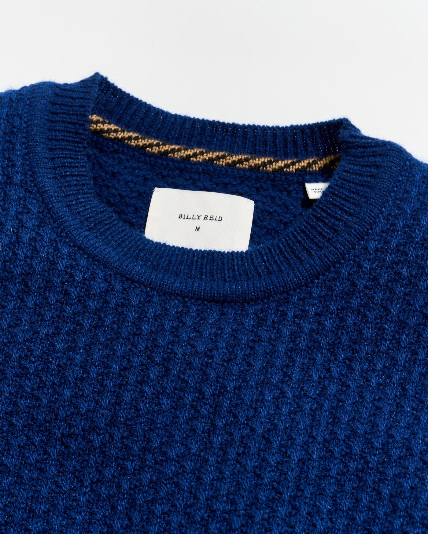 Close-up of a blue sweater with a brand label on a white background