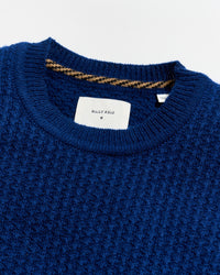 Close-up of a blue sweater with a brand label on a white background