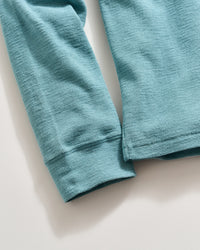Close-up of a light blue, long-sleeve waffle-knit shirt laid flat on a white surface, showing the textured fabric pattern and details of the cuffs and hem.
