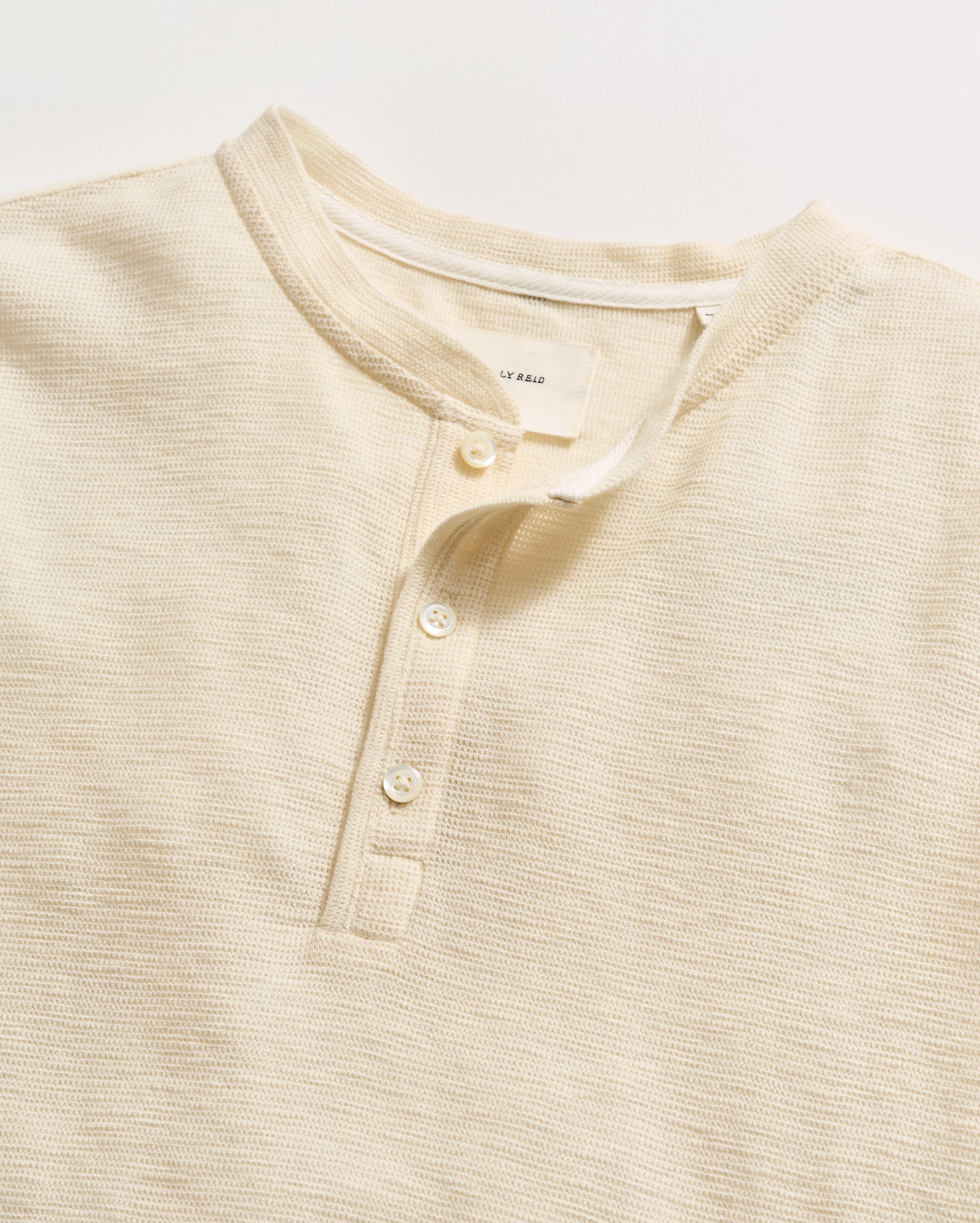 Beige henley shirt with button details on a light background