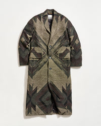 A long, patterned overcoat with a geometric design in earthy tones, featuring a notched collar, button closure, and two large front flap pockets, displayed against a plain white background.