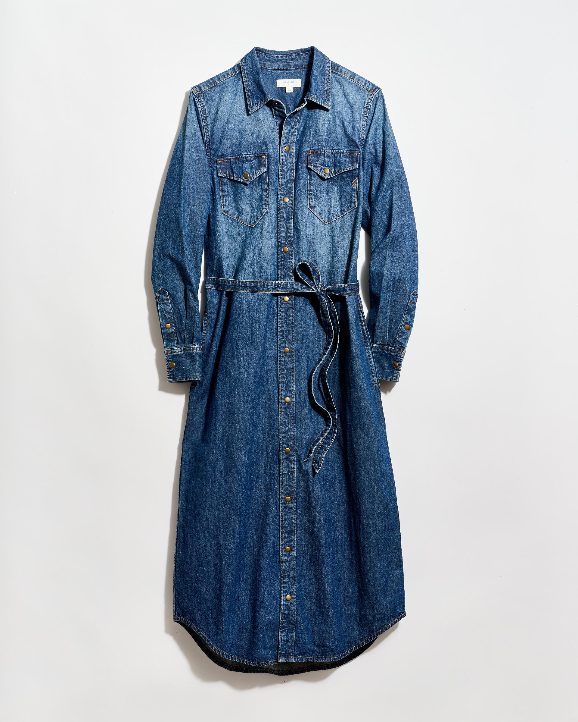 A long-sleeve, button-down denim dress with a collar, two chest pockets, and a matching denim waist tie, laid flat on a white background.