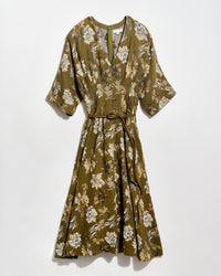 Olive green, knee-length dress with a white and tan floral pattern, short wide sleeves, a V-neckline, and a thin matching belt tied at the waist. The dress is displayed against a plain white background.