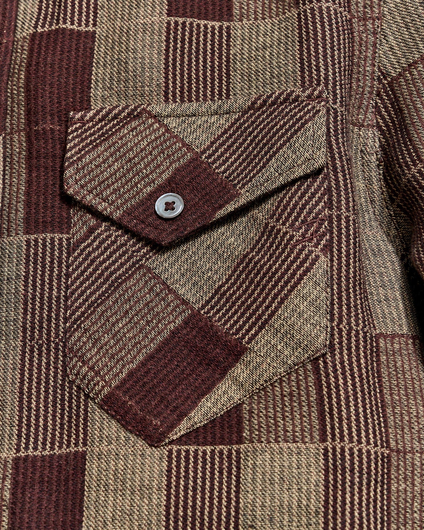 Close-up of a brown and beige plaid fabric with a button pocket detail