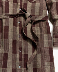 Close-up of a brown and beige checkered dress with buttons on a white background