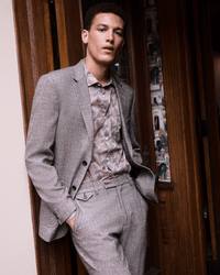 Man wearing a gray suit with a patterned shirt in an indoor setting