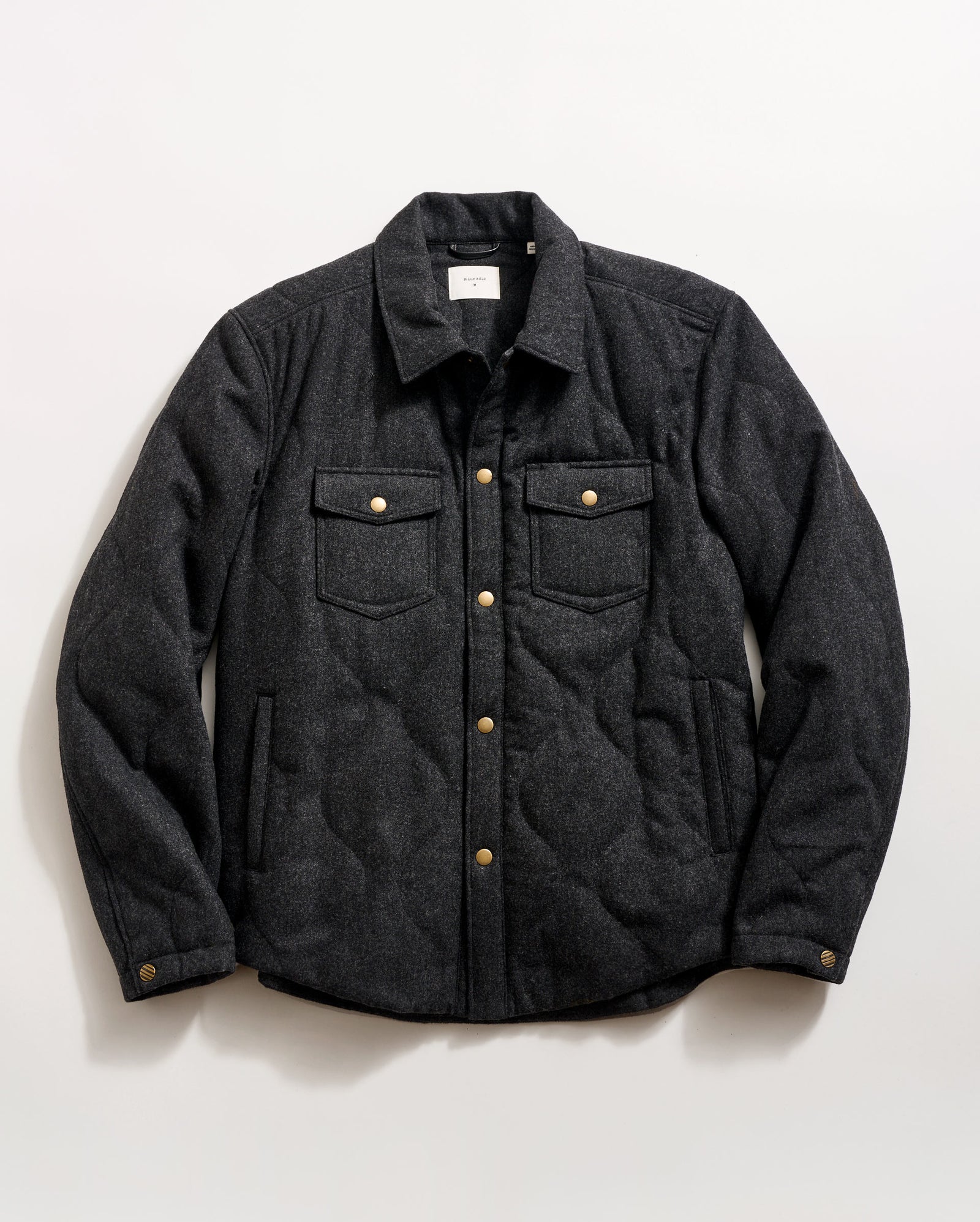 A dark gray quilted jacket with a collar, front snap buttons, two chest pockets with flaps, and two side pockets, laid flat on a white background.