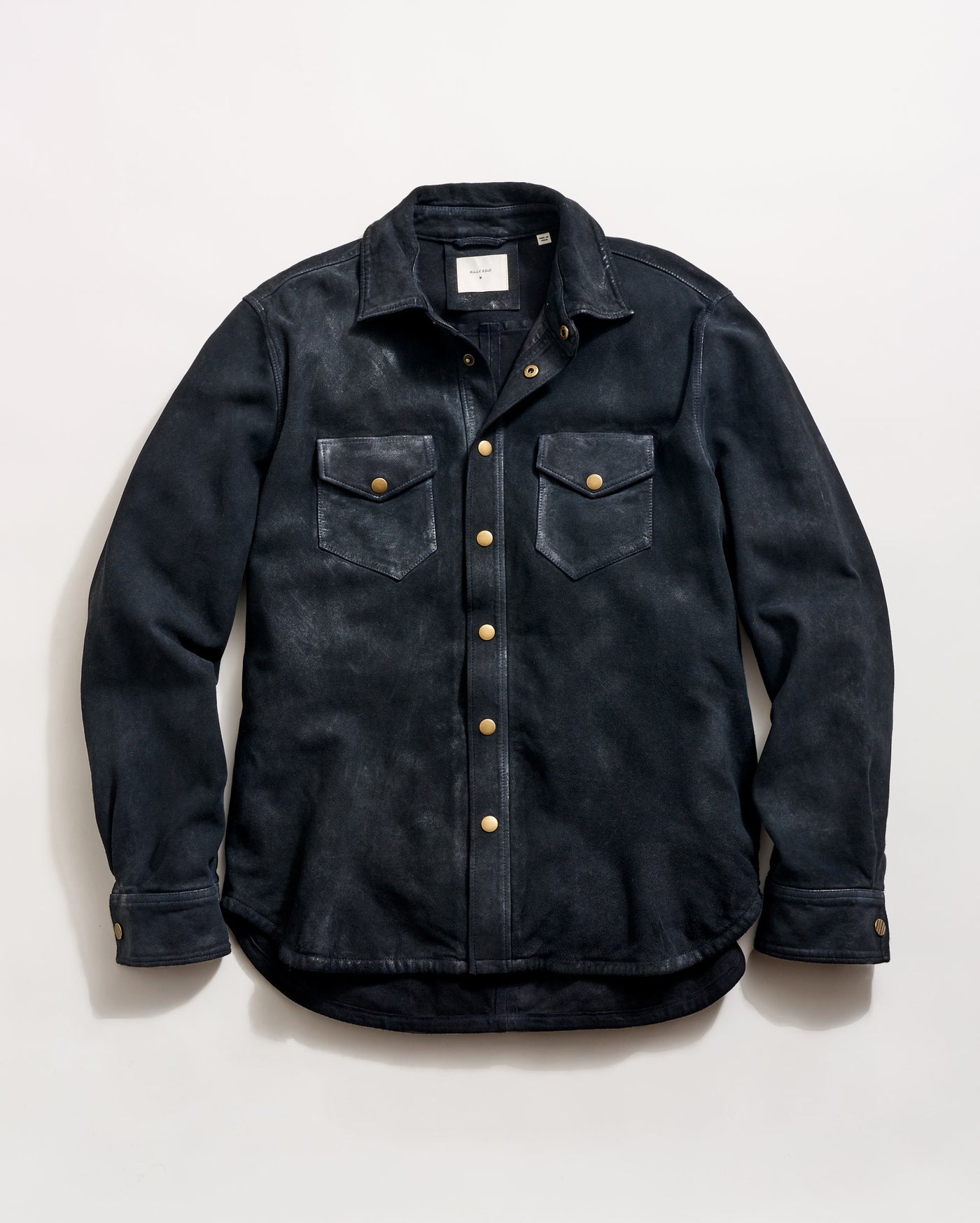 A black button-up shirt jacket with two chest pockets, gold-colored snap buttons, and a folded collar, laid flat on a light background.