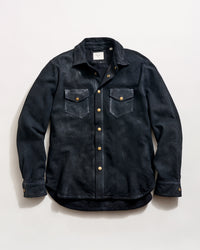 A black button-up shirt jacket with two chest pockets, gold-colored snap buttons, and a folded collar, laid flat on a light background.
