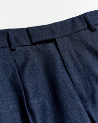 Close-up of blue pleated pants with a light gray background