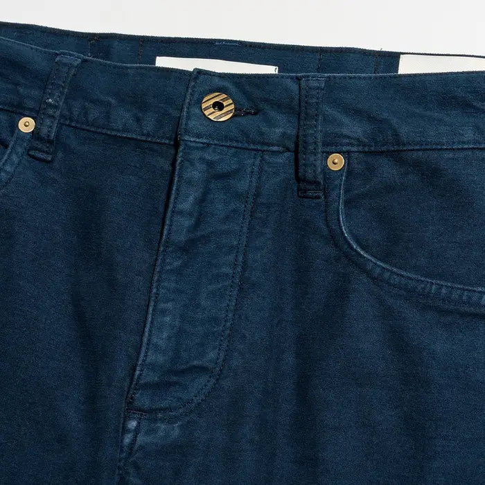 Close-up of blue denim pants with gold buttons on a white background