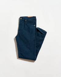 A pair of neatly folded dark blue jeans with visible front pockets and a brown leather patch on the waistband, displayed on a plain white background.
