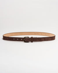 A brown suede leather belt with a brass buckle, laid flat in a circular shape on a white background. The interior of the belt is tan, and several adjustment holes are visible.