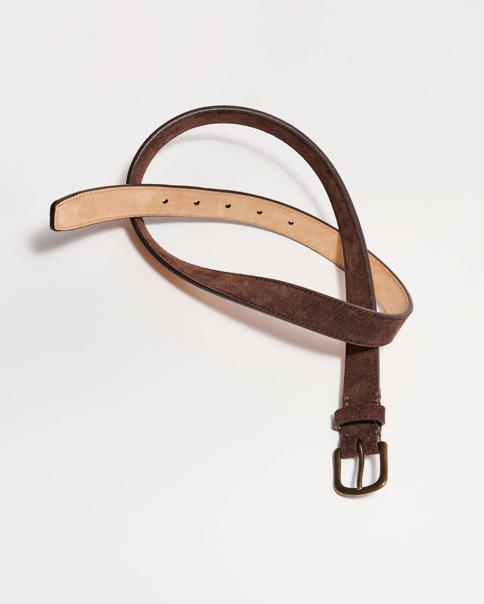 A brown suede belt with a metal buckle is laid out on a white background, with its tail curled into a loose loop.