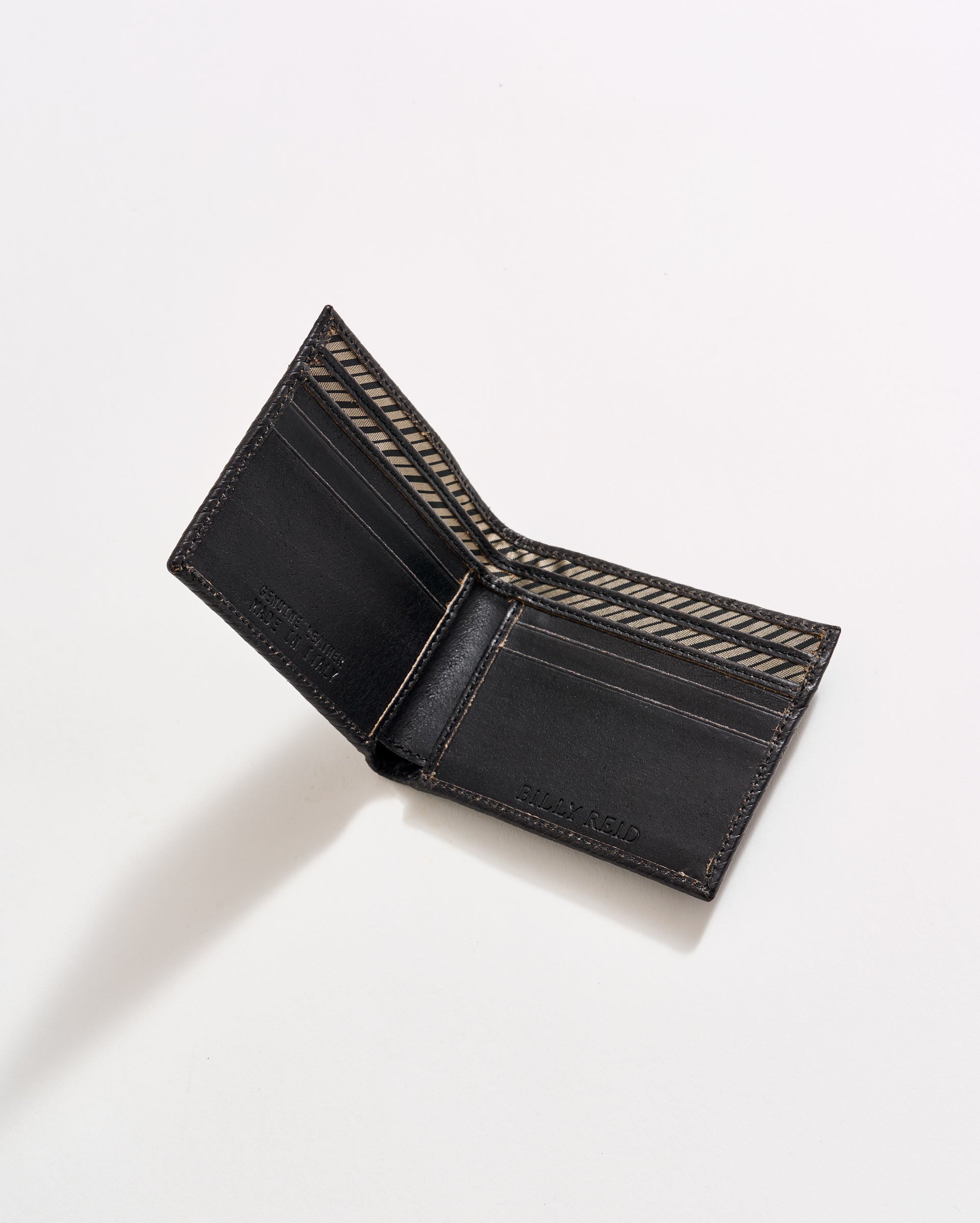 An open black leather wallet with brown stitching, showing multiple card slots and a patterned interior, photographed on a white background.