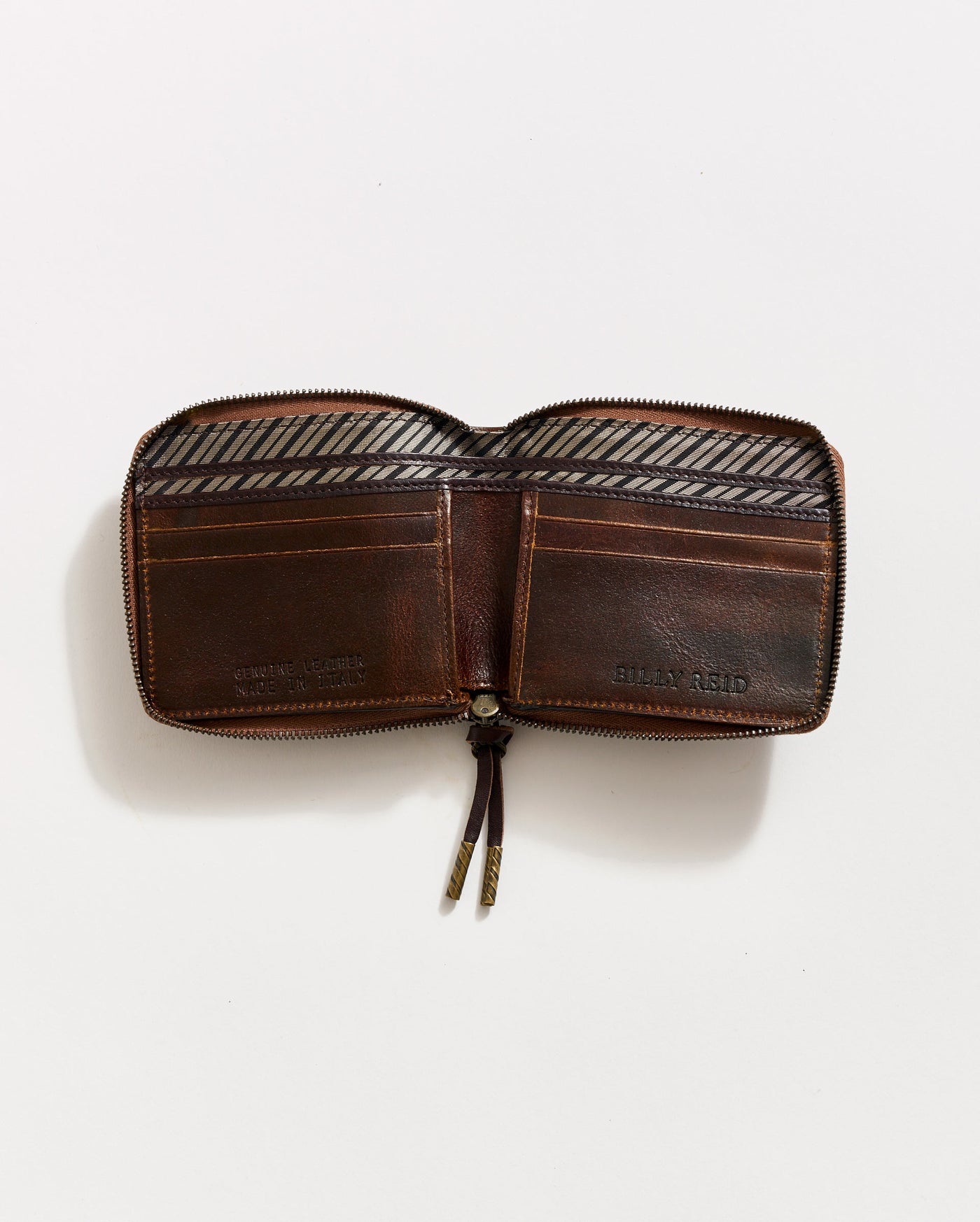 A brown leather wallet with a zipper is open, showing multiple card slots and compartments. The interior features a striped fabric lining, and the wallet rests on a plain white background.