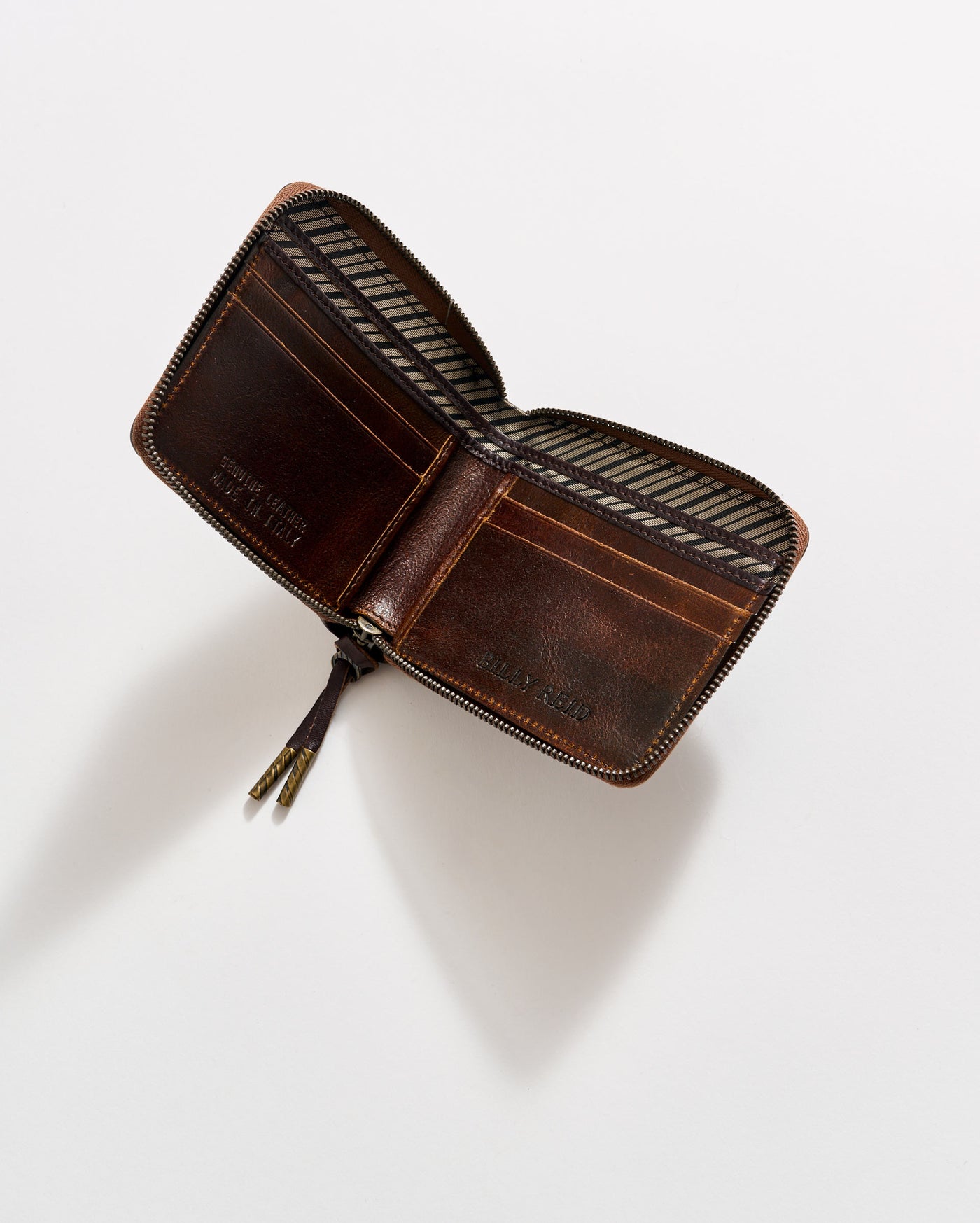 A brown leather zippered wallet is open, showing striped fabric lining and empty card slots, placed on a plain white background.