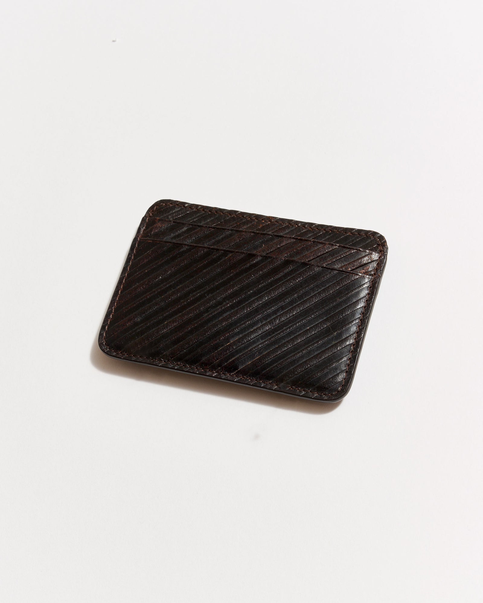 A dark brown leather cardholder with diagonal embossed lines, photographed on a plain white background.