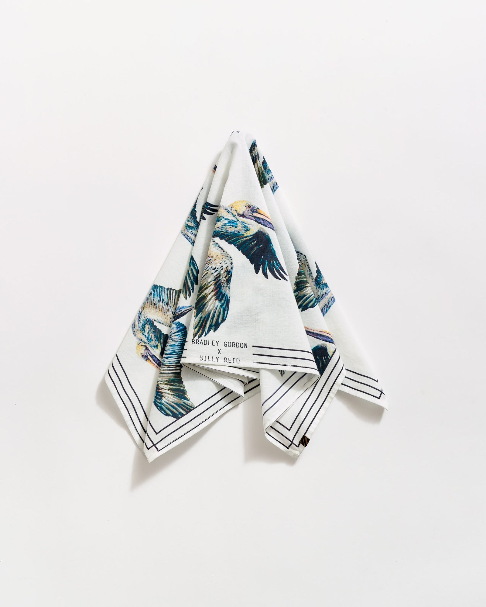 A folded white handkerchief hangs against a white background, featuring colorful bird illustrations and black border lines. The text Bradley Gordon and Billy Reid is visible near one corner.